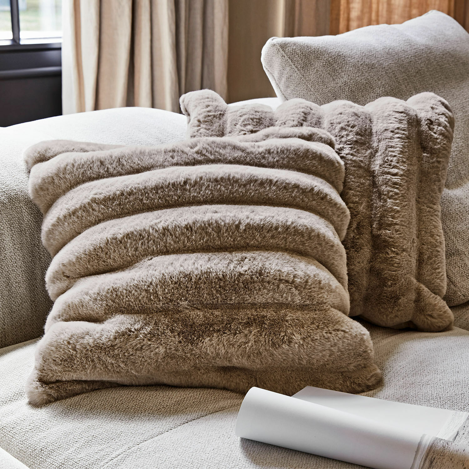 Coussin décoratif en fausse fourrure beige sur canapé clair pour salon cosy
