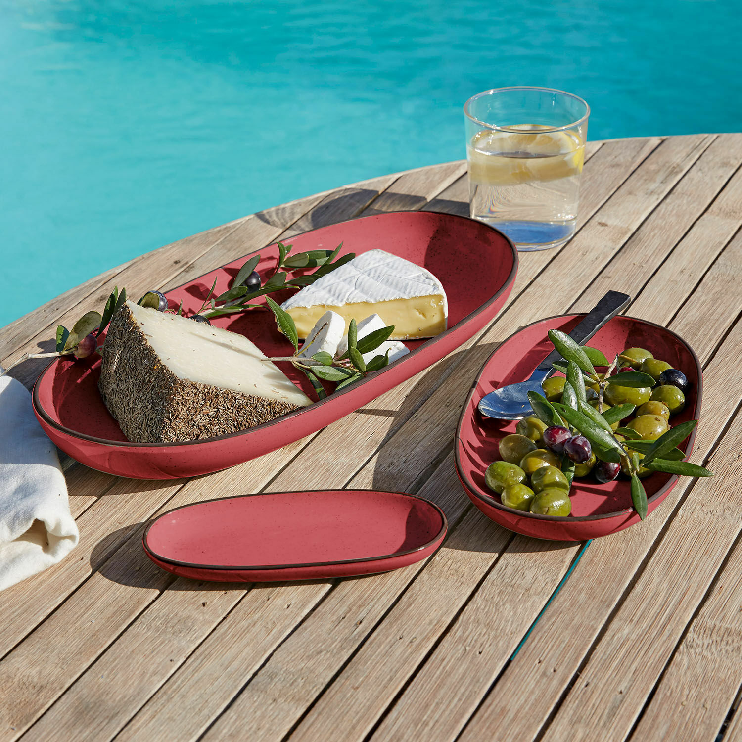 Lot de 3 plateaux de service Biarré Assiettes ovales en céramique rouge avec fromage et olives sur table en bois près de la piscine