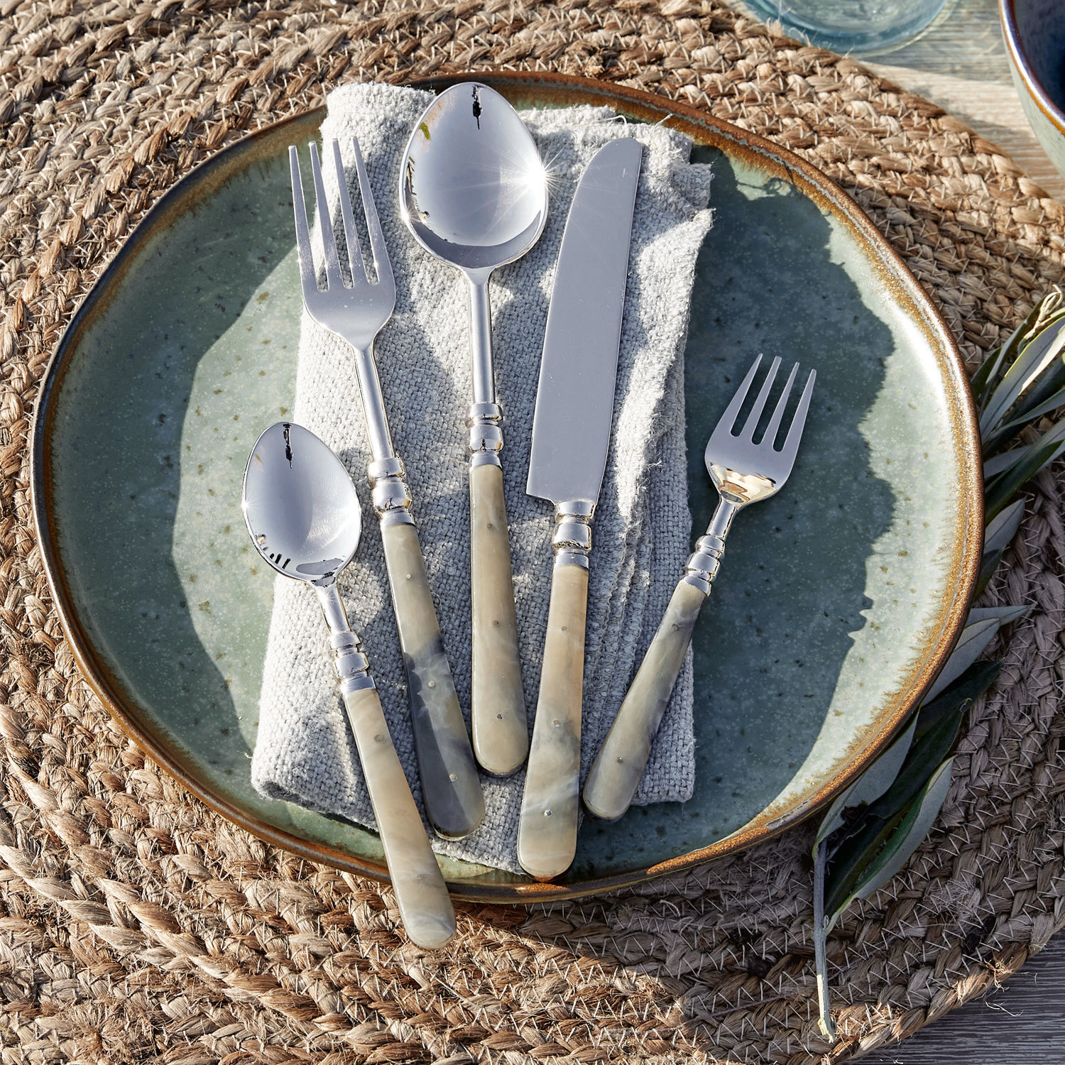 Lot de 5 couverts Kumar Ensemble de couverts avec manches en nacre beige sur une assiette verte, décoration de table élégante