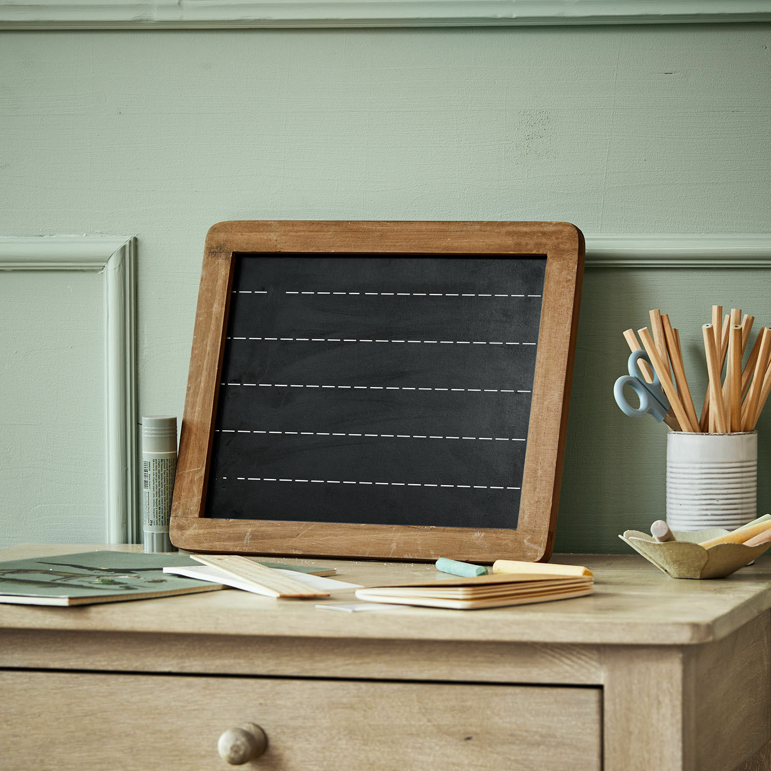 Tableau Kanza Tableau noir avec cadre en bois sur un bureau avec craies et fournitures de bureau pastel
