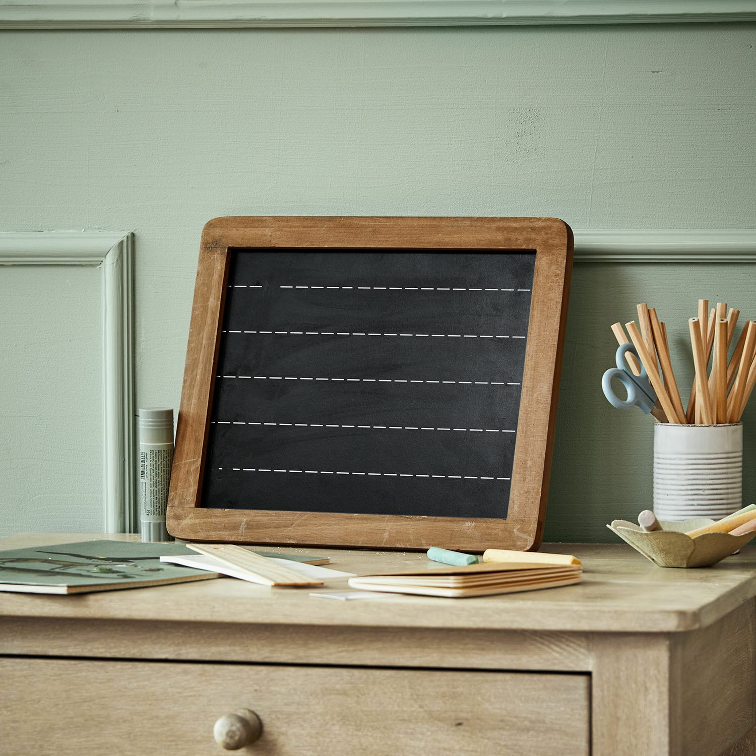 Tableau Kanza Tableau noir avec cadre en bois sur un bureau avec craies et fournitures de bureau pastel