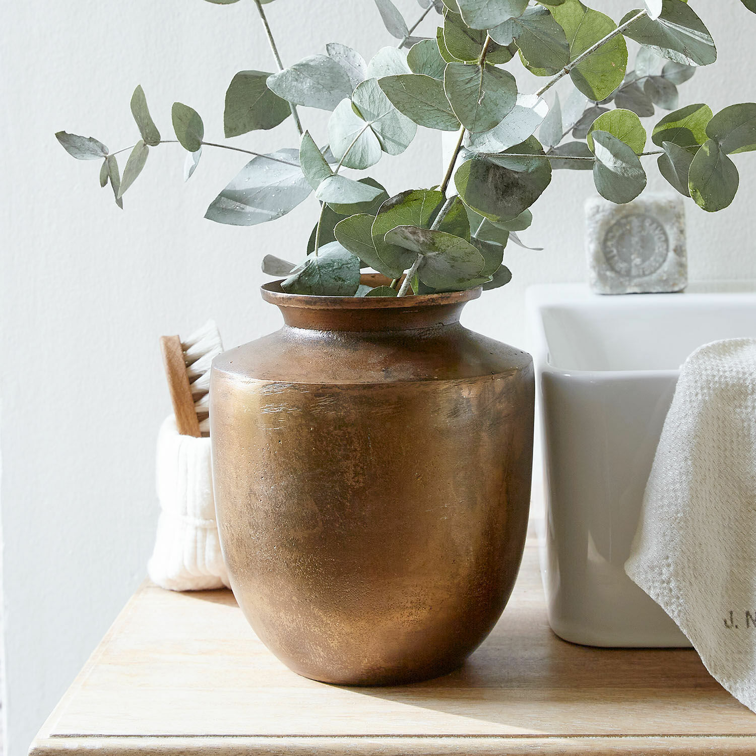 Vase Toulane Vase en laiton avec feuilles d'eucalyptus vertes sur une table en bois dans un intérieur clair