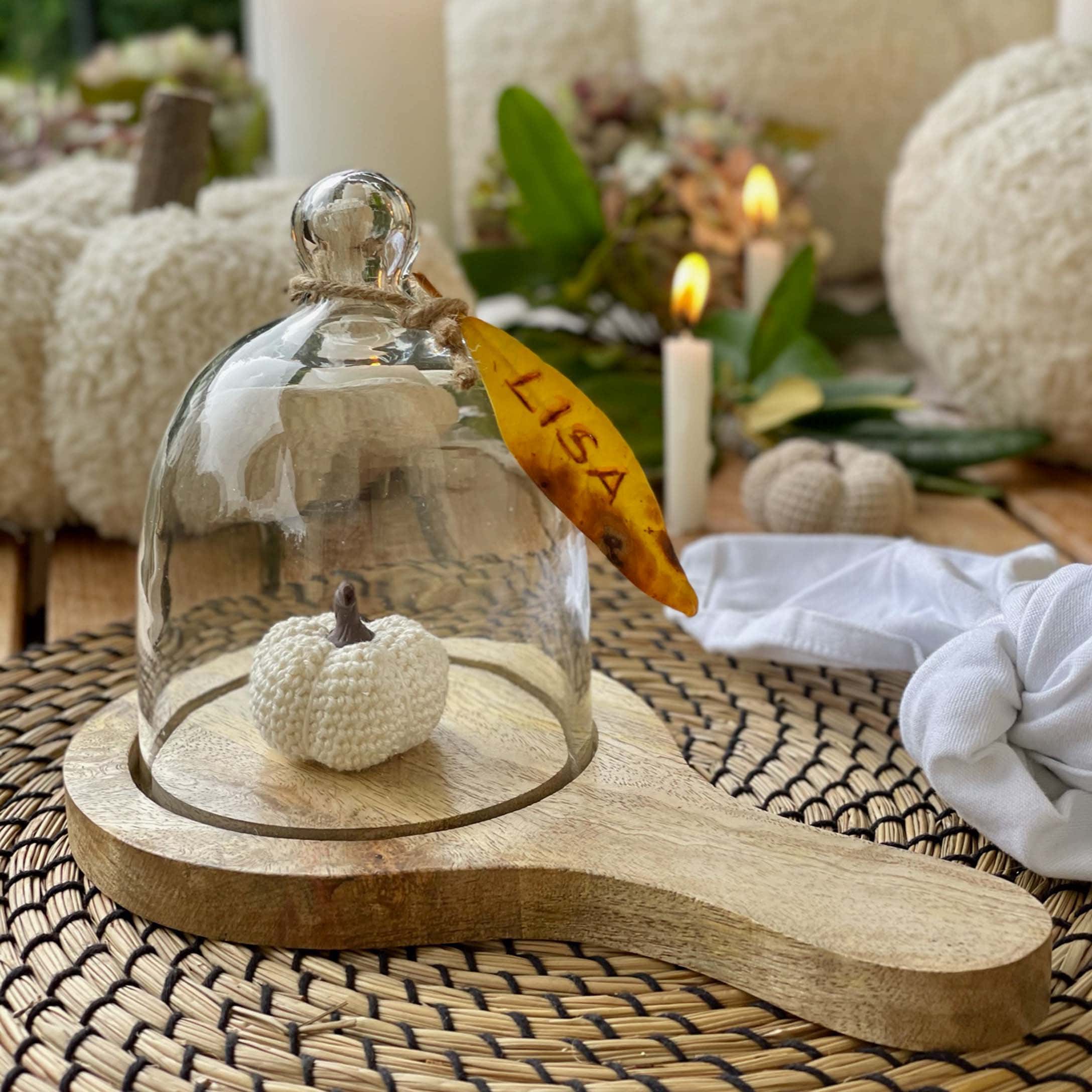 Cloche en verre sur socle en bois avec petite citrouille blanche au crochet pour décoration automnale