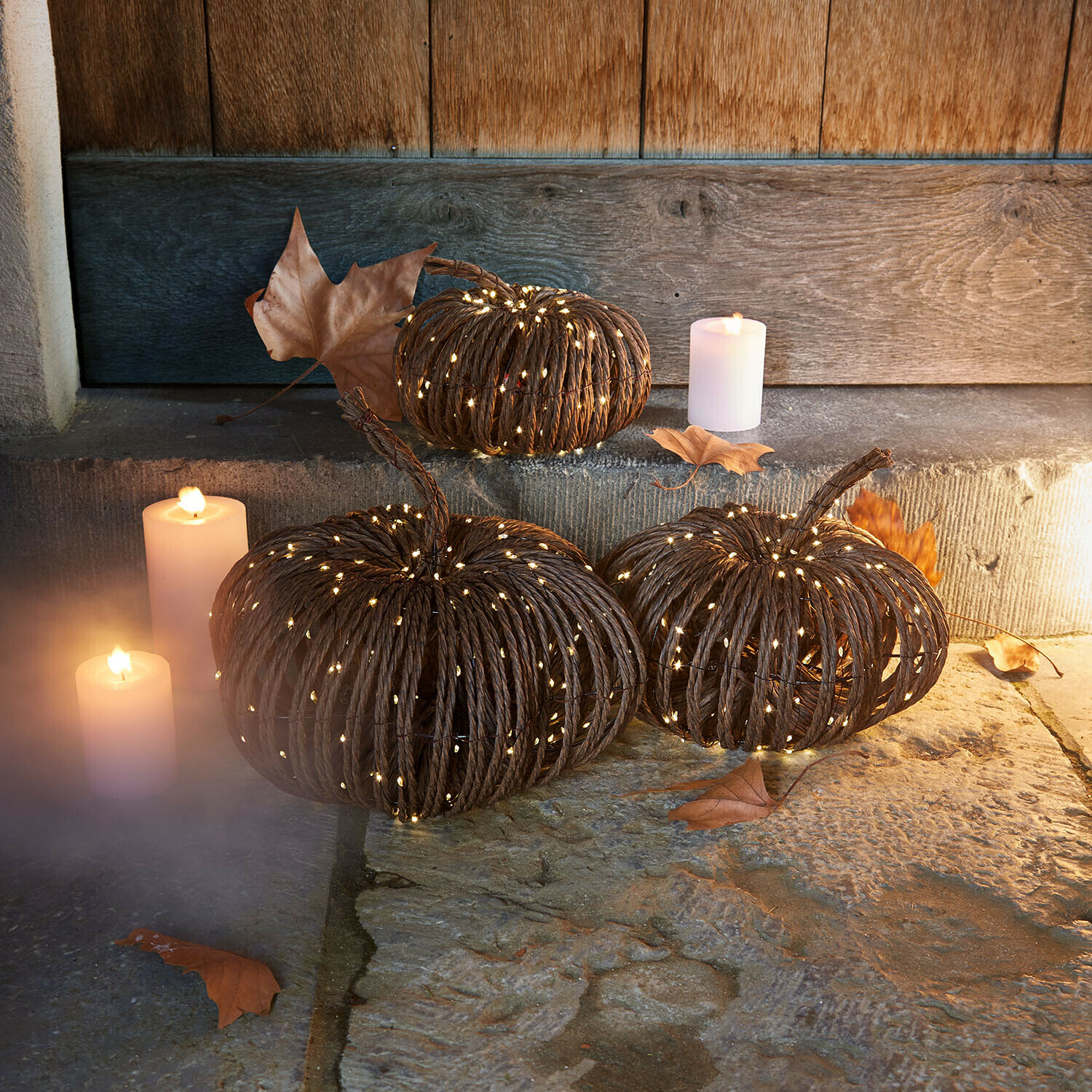 Lot de 3 citrouilles à LED Ysolann Citrouilles décoratives en corde sombre avec éclairage LED doux et bougies sur sol en pierre rustique