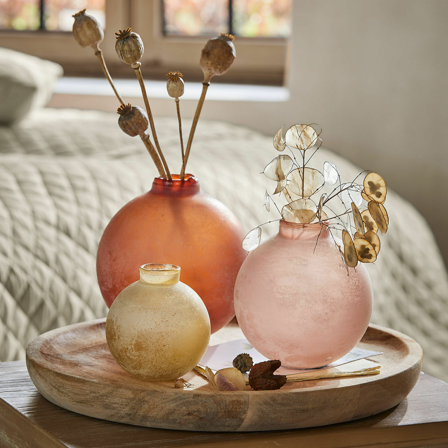 Lot de 3 vases Imbrianno Trois vases en verre mat orange, rose et jaune sur un plateau en bois avec des fleurs séchées décoratives