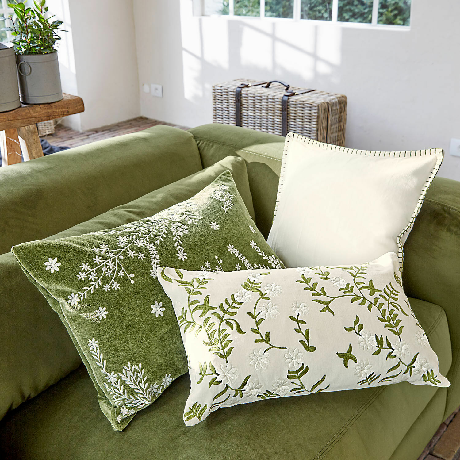 Lot de 3 housses de coussins Iplique Ensemble de trois coussins décoratifs brodés en vert et crème sur un canapé vert