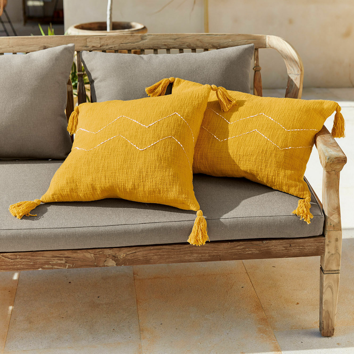 Lot de 2 housses de coussins Misstos Coussins décoratifs jaunes en coton avec pompons sur un banc en bois avec assise grise