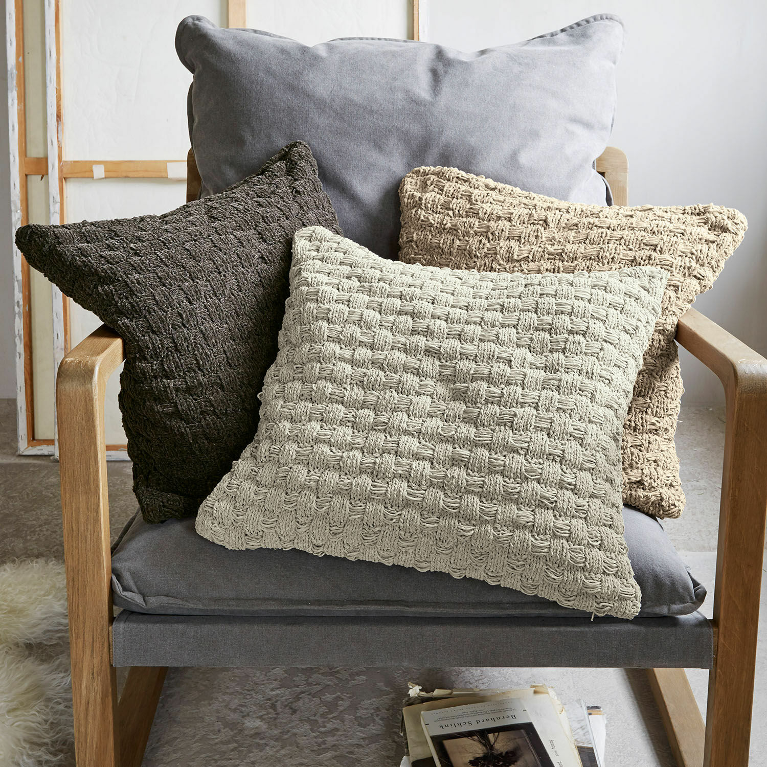 Lot de 3 housses de coussins Antier Ensemble de trois coussins décoratifs en tissu tressé beige et marron sur un fauteuil gris