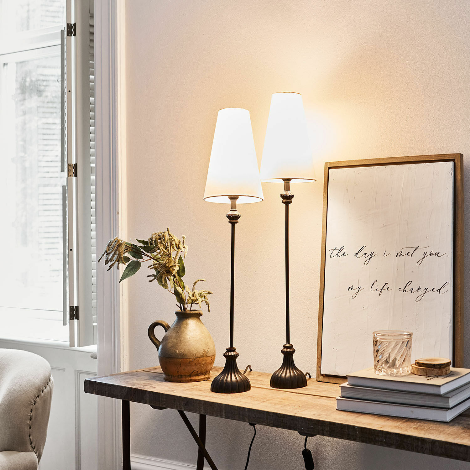 Lot de 2 lampes à poser Ambrosse Deux lampes de table en métal noir avec abat-jours blancs sur une table en bois dans un intérieur lumineux