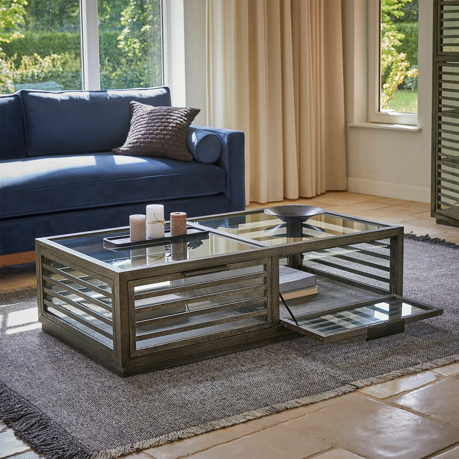 Table basse Trowbridge Table basse en bois foncé et verre avec compartiment ouvrant sur tapis dans un salon lumineux