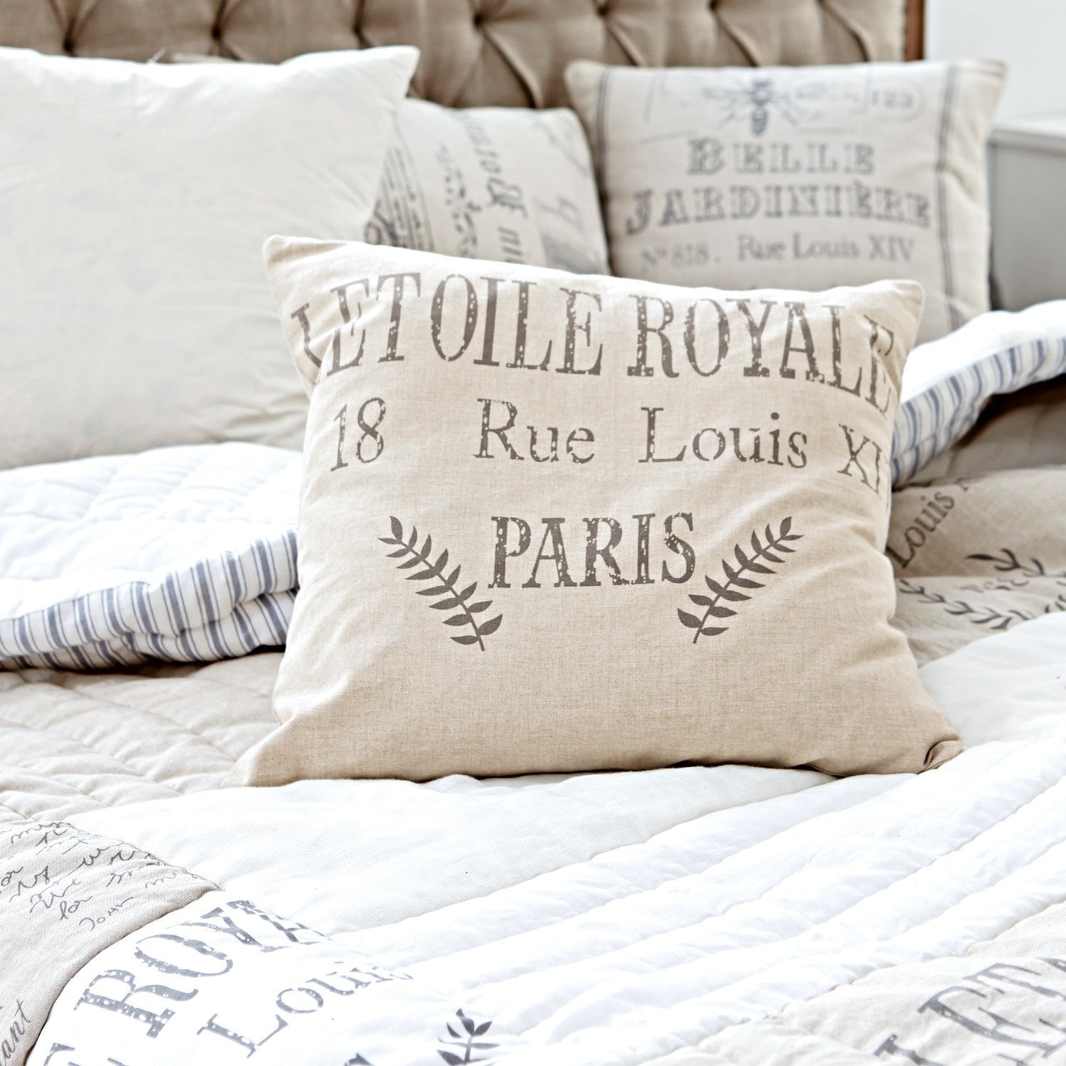 Housse de coussin Etoile Royal Coussin décoratif beige en lin avec impression texte vintage sur un lit confortable