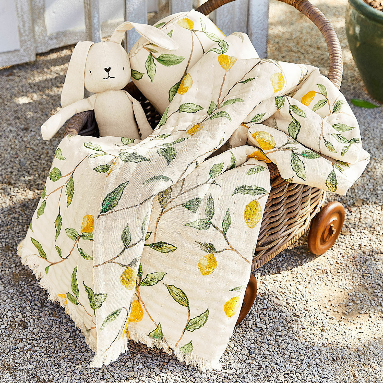 Plaid Palerina Plaid en coton crème avec motifs citrons jaunes et feuilles vertes dans un panier en osier