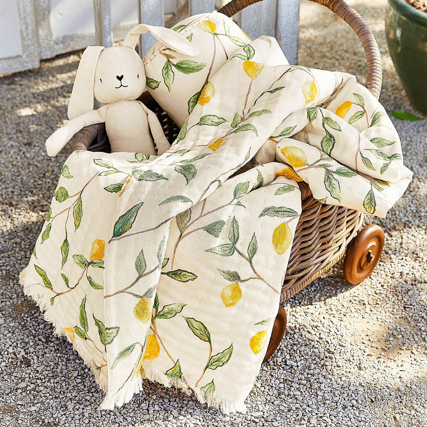 Plaid Palerina Plaid en coton crème avec motifs citrons jaunes et feuilles vertes dans un panier en osier