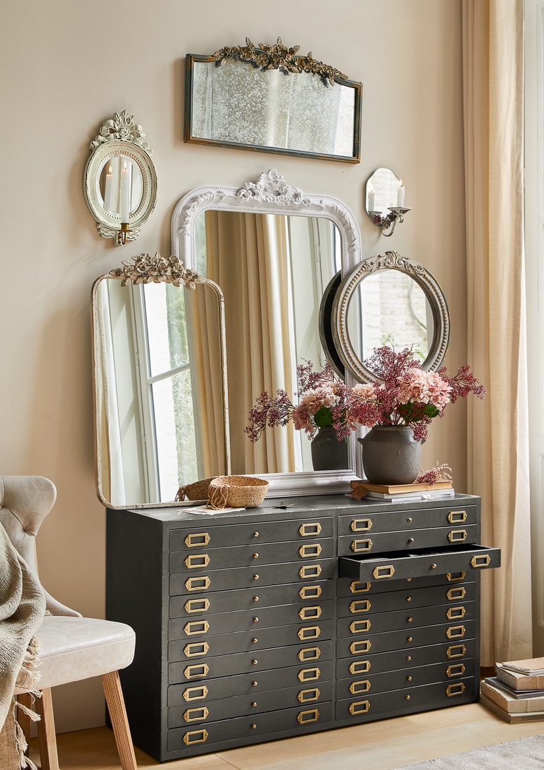 Commode noire en métal avec de nombreux tiroirs et miroirs décoratifs vintage accrochés au mur