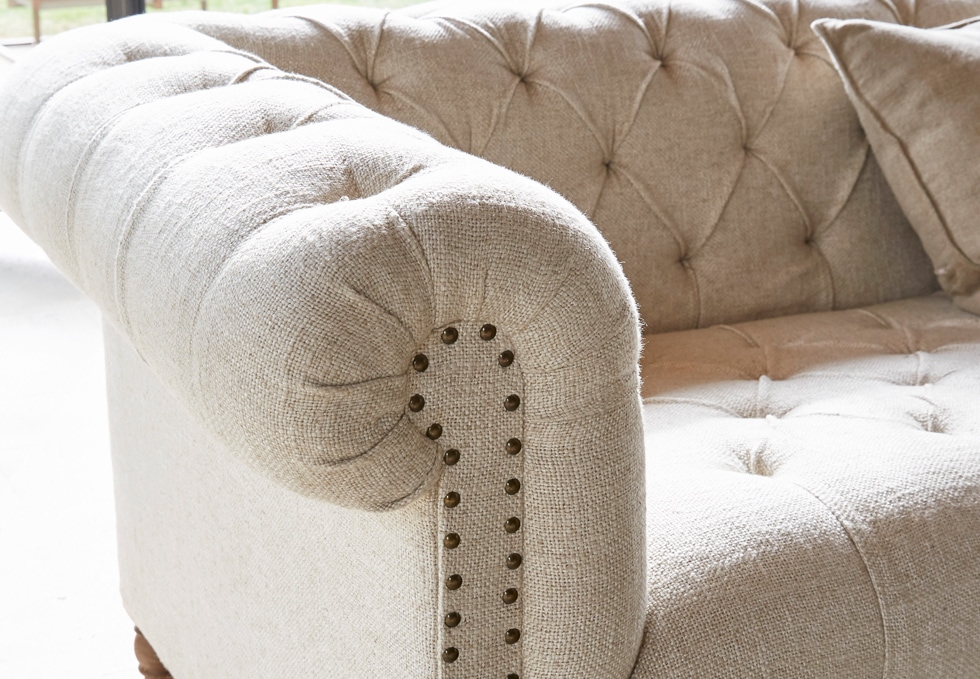Canapé classique beige en tissu avec dossier capitonné et clous décoratifs pour salon élégant