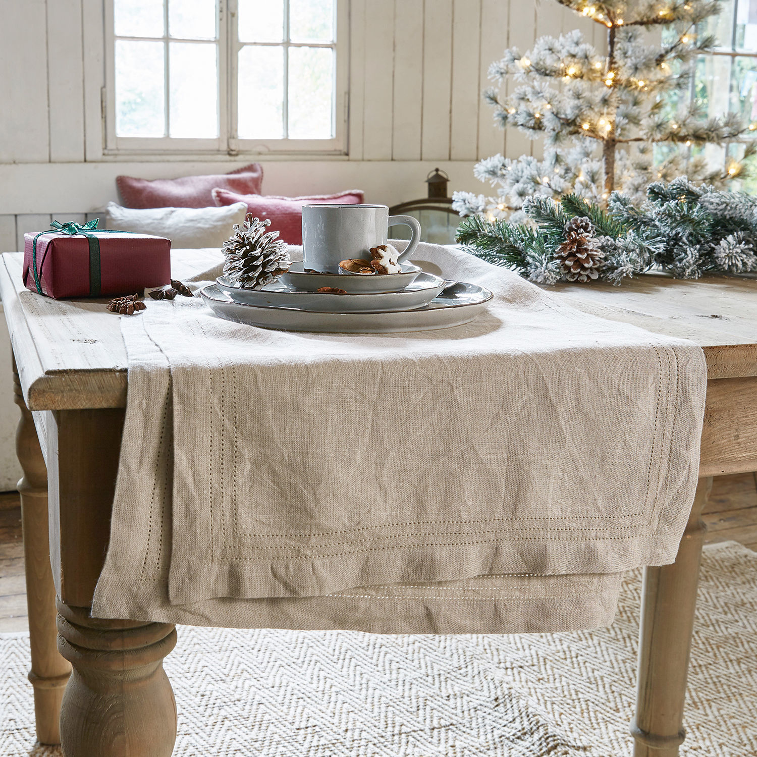Chemin de table Brion Chemin de table en lin beige sur table en bois avec décorations de Noël et vaisselle grise