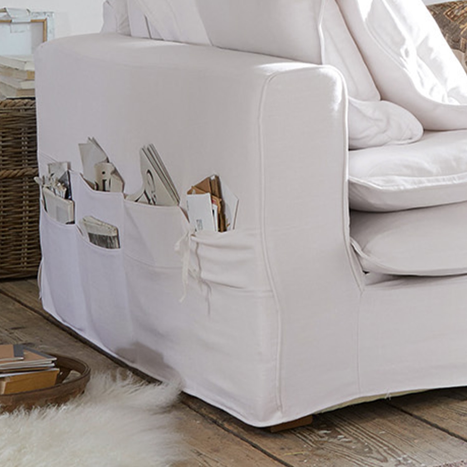 Canapé blanc en coton avec poches latérales pour magazines et livres dans un salon chaleureux