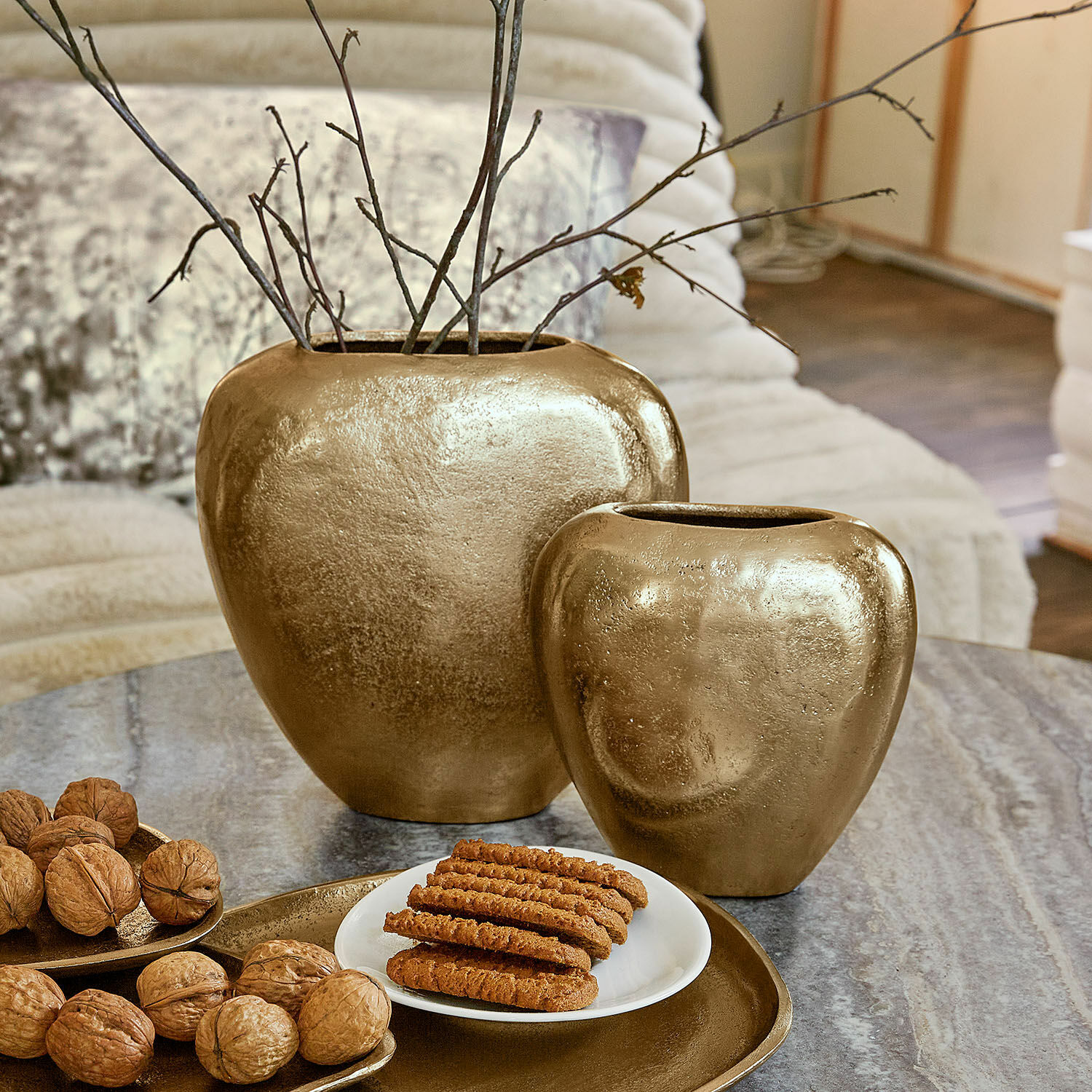 Lot de 2 vases Cezelle Ensemble de deux vases en céramique dorée sur une table avec noix et biscuits dans un salon