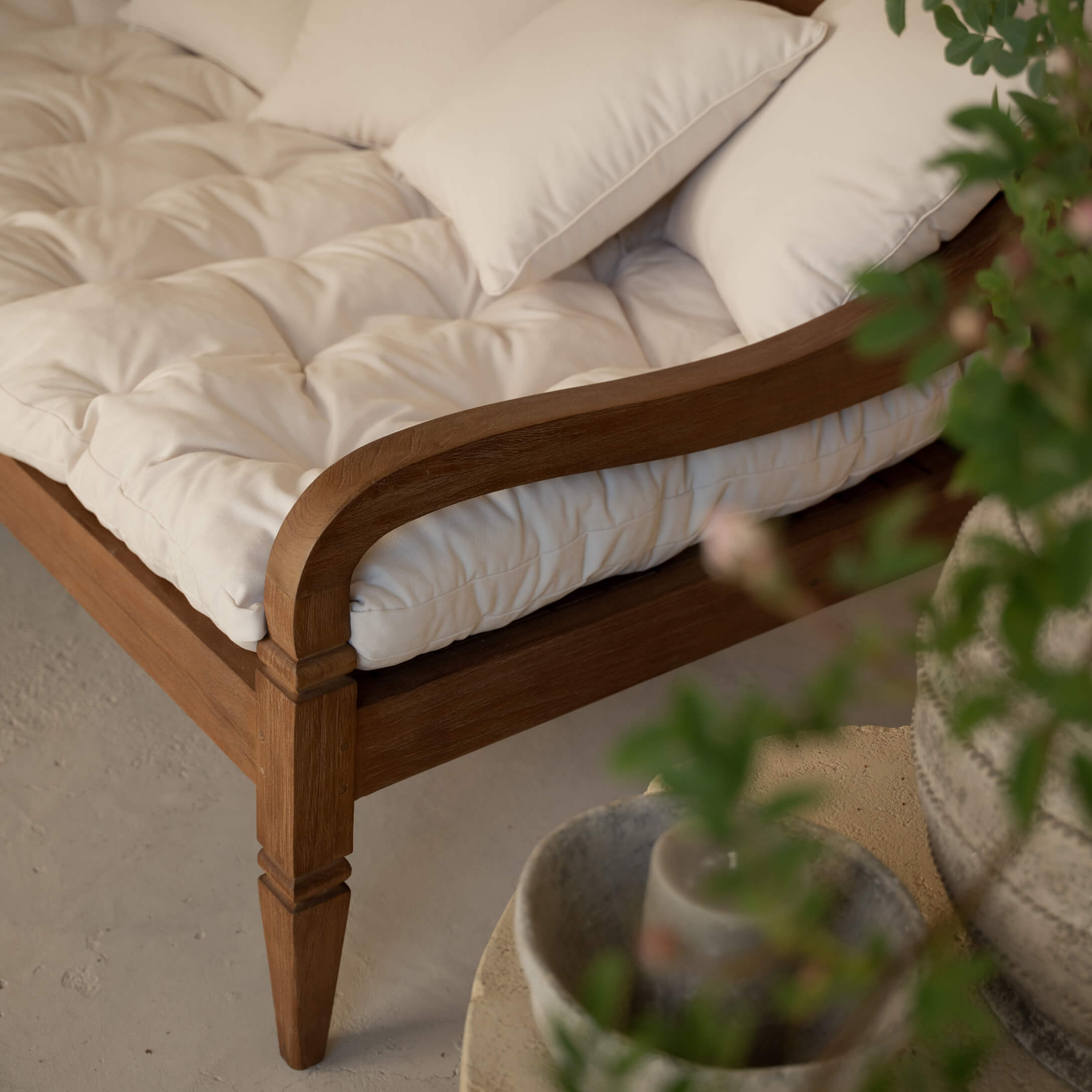Détail d'un canapé en bois avec coussin matelassé crème et coussins moelleux décoratifs