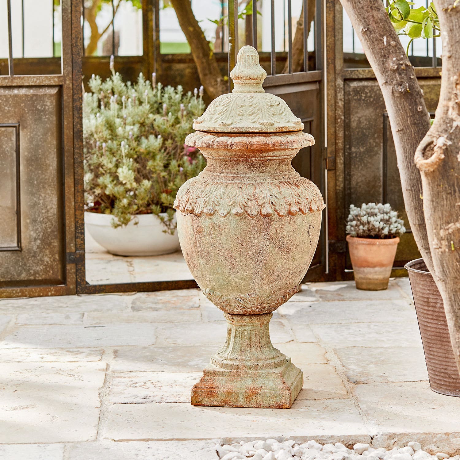 Objet décoratif Persephone Vase décoratif en terre cuite couleur naturelle sur sol en pierre avec plantes en arrière-plan