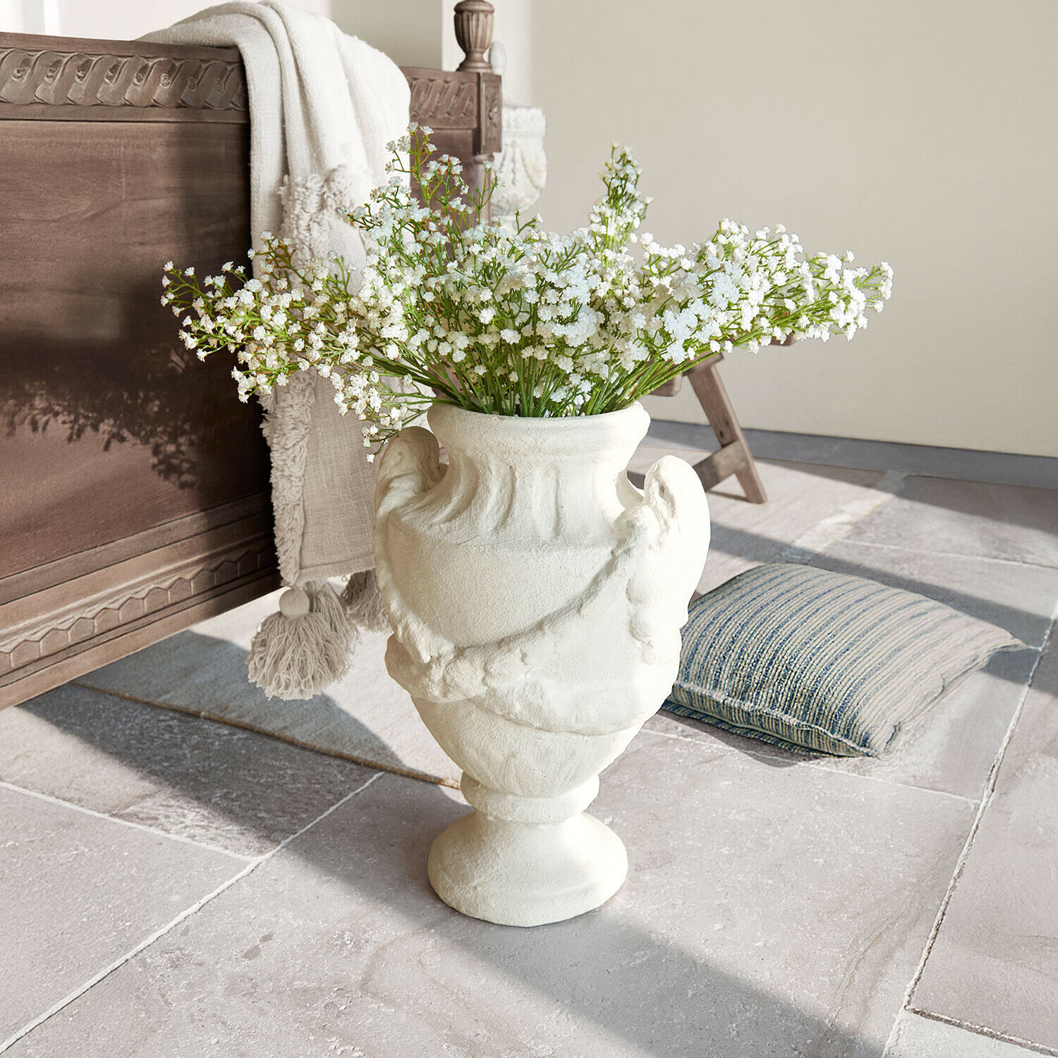 Cache-pot Chaverny Vase en céramique blanche avec motif décoratif et fleurs blanches sur sol en pierre