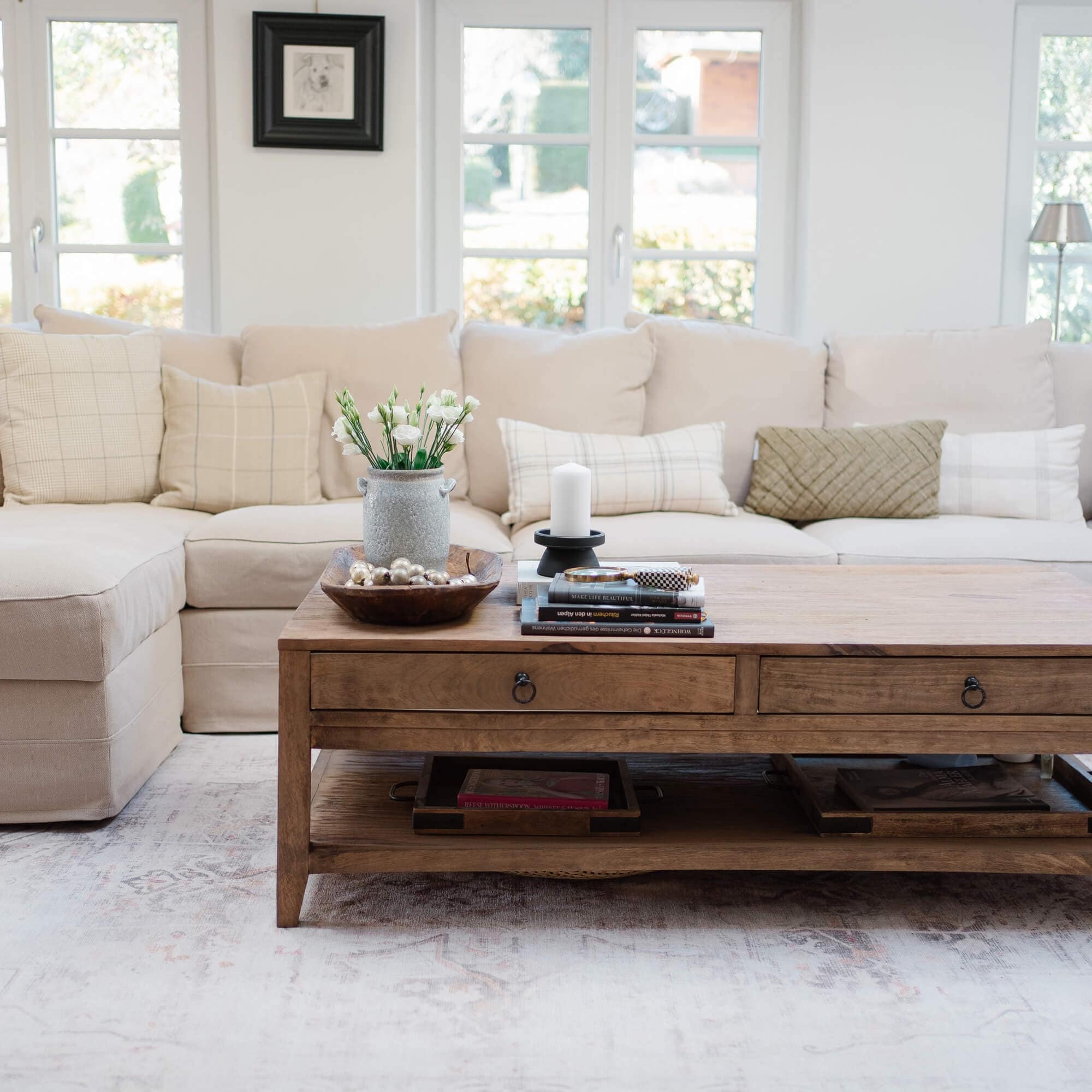 Table basse en bois avec tiroirs et décorations devant un canapé beige lumineux