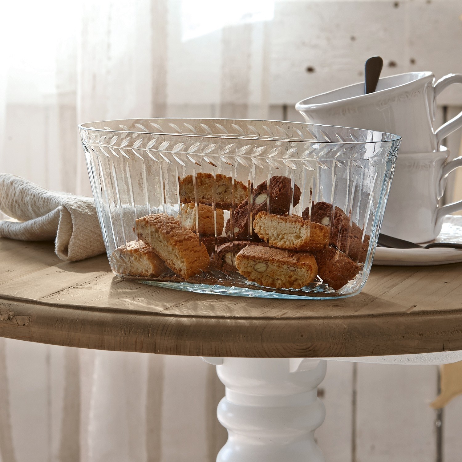 Coupe Malinda Bol en verre transparent avec motif décoratif rempli de biscuits sur une table en bois clair
