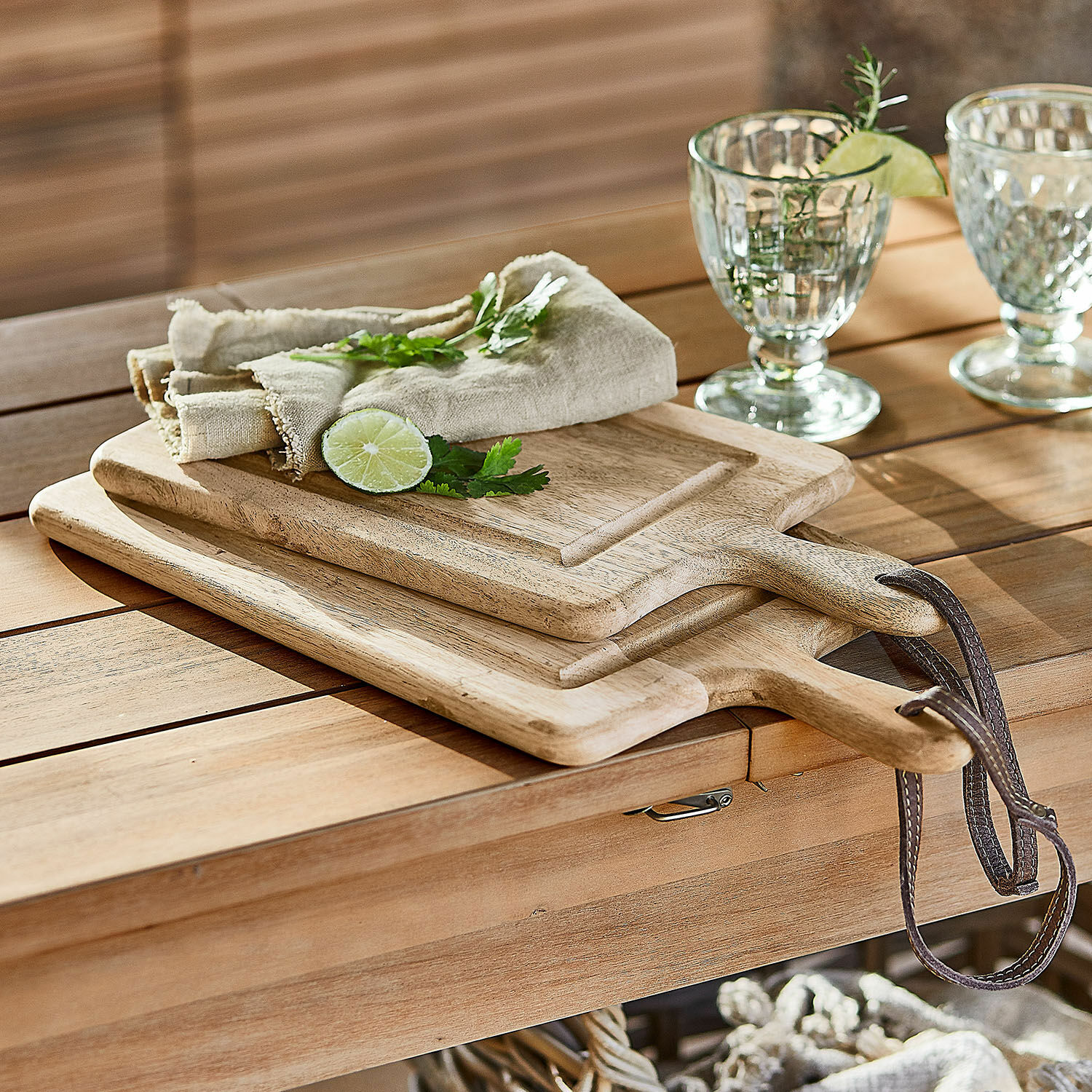 Lot de 2 planches à découper Lestino Planches à découper en bois avec poignées et lanières en cuir sur une table en bois naturel