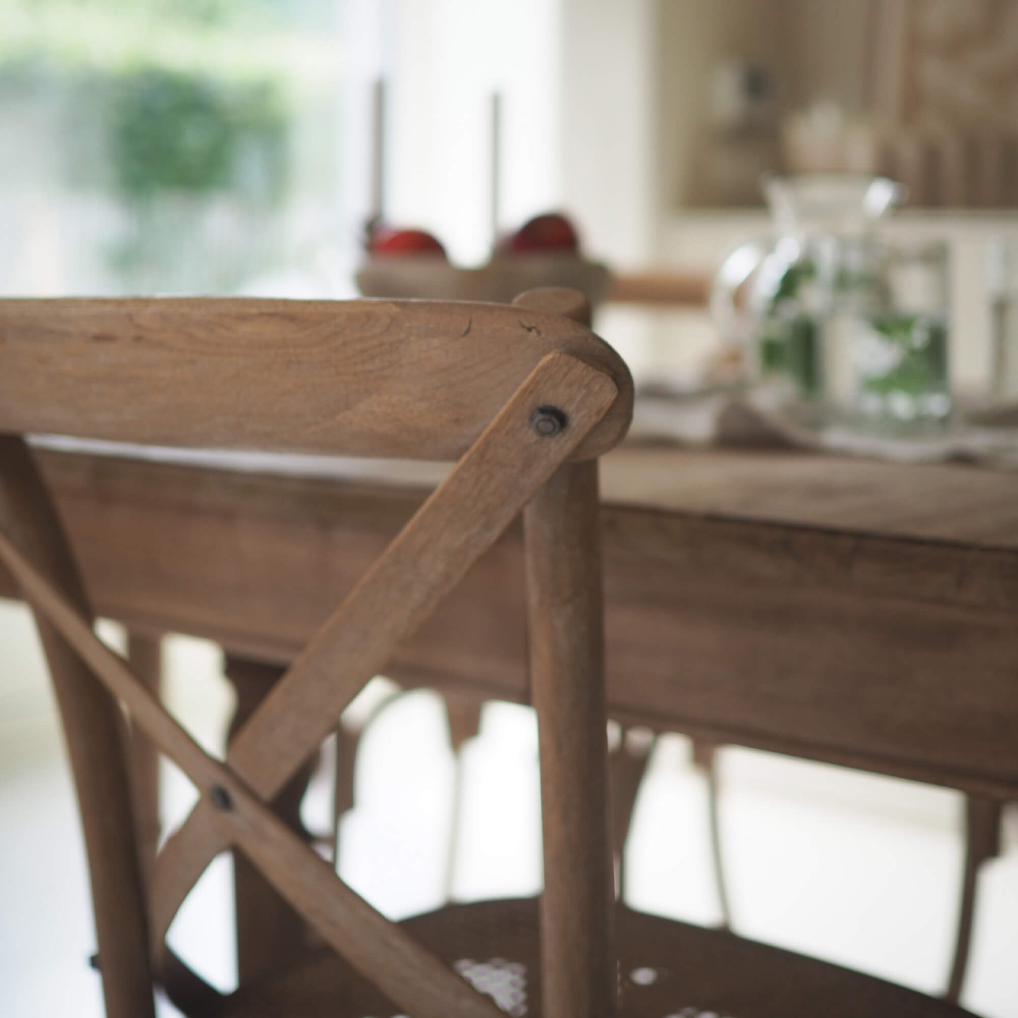 Chaise en bois clair avec dossier en X dans une salle à manger lumineuse et chaleureuse