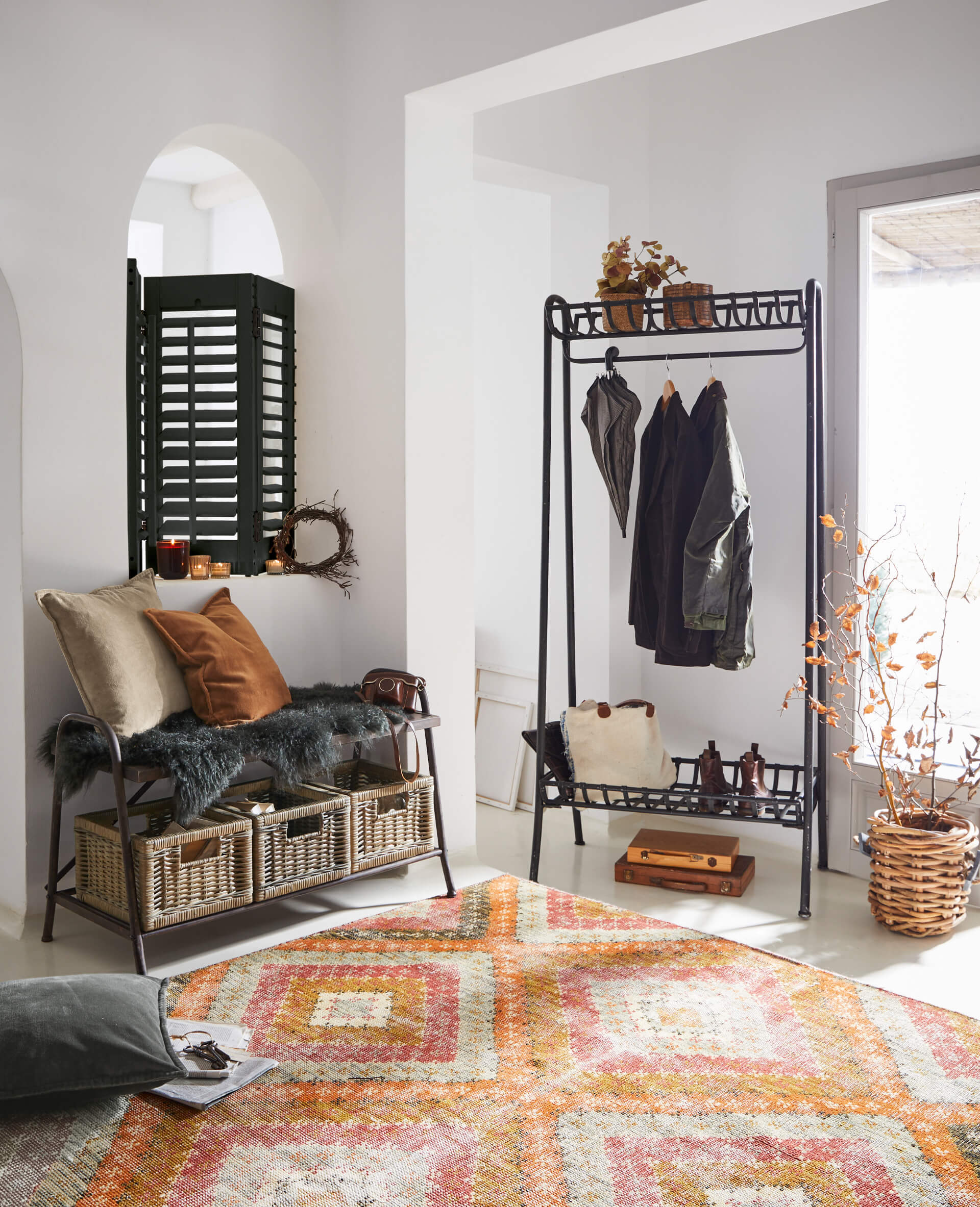 Intérieur chaleureux avec porte-manteau en métal, banc avec paniers en osier et tapis coloré au sol