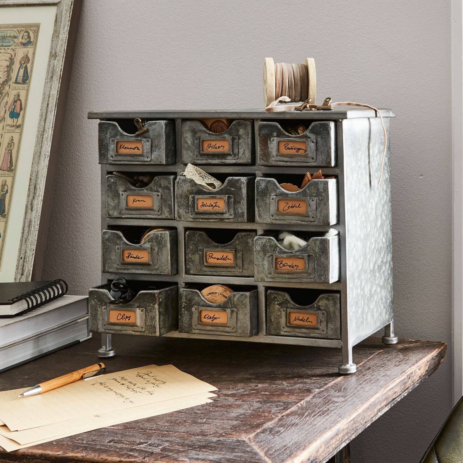 Meuble de rangement Serena Petit meuble en métal gris avec 12 tiroirs pour organiser petits objets et accessoires de bureau.