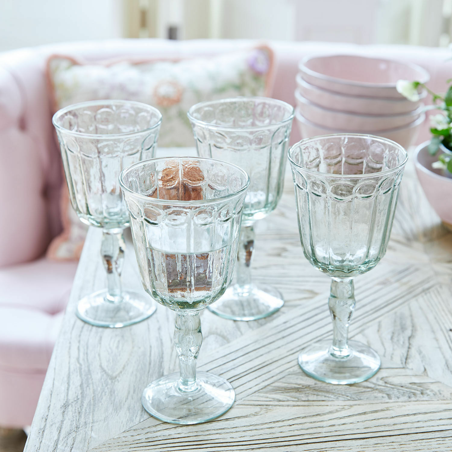 Lot de 4 verres Jolielle Ensemble de quatre verres transparents à pied avec motif décoratif sur une table en bois clair