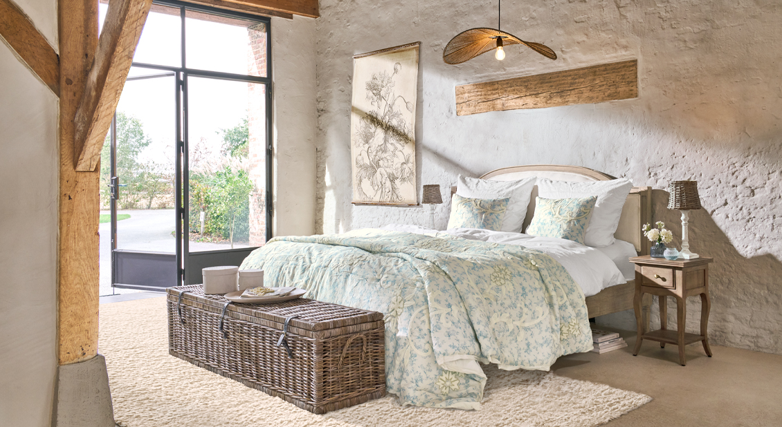 Chambre chaleureuse avec lit en bois et literie claire à motif floral, matériaux naturels et décorations