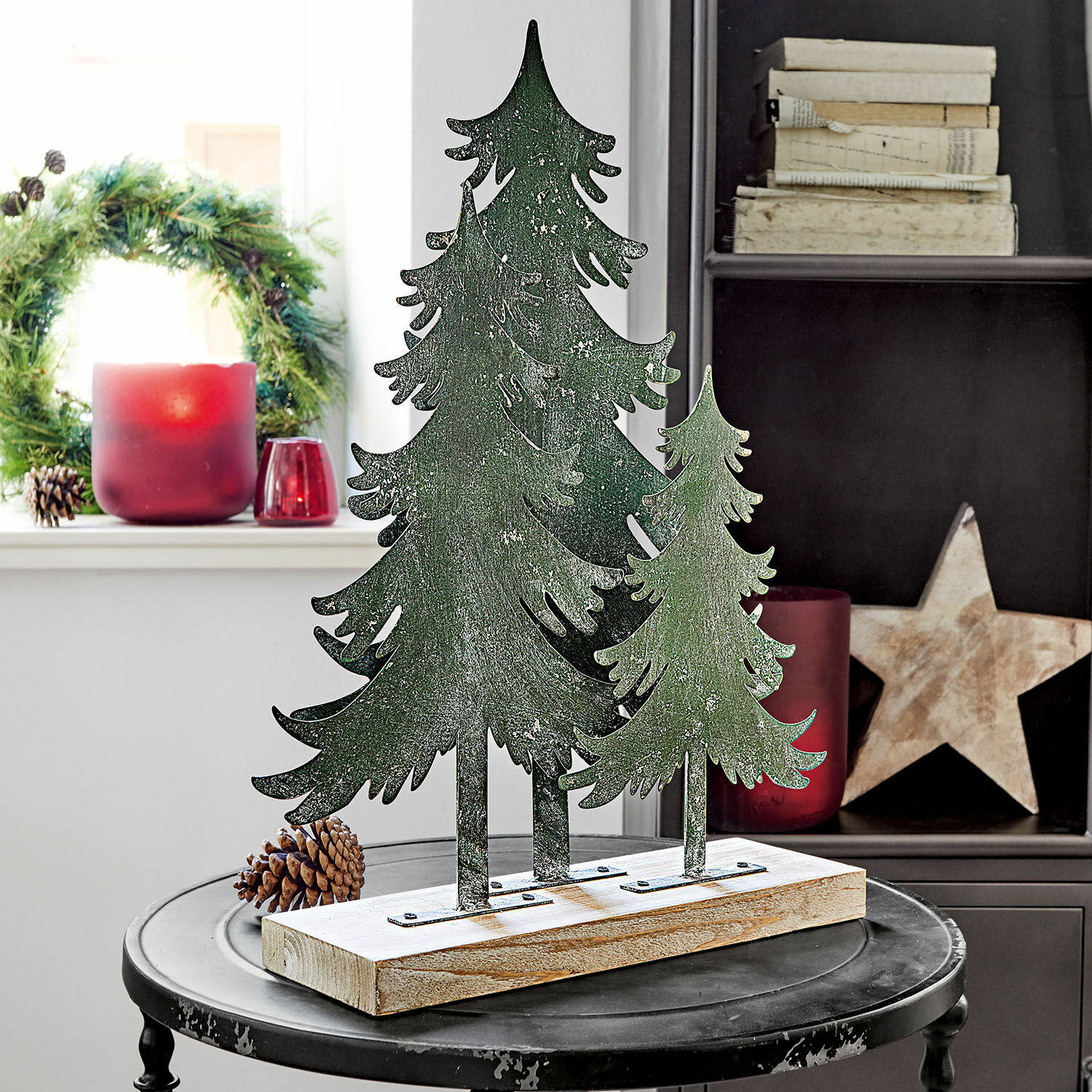 Arbres décoratifs Filiz Décoration de Noël avec sapins verts en métal sur base en bois posée sur une table noire