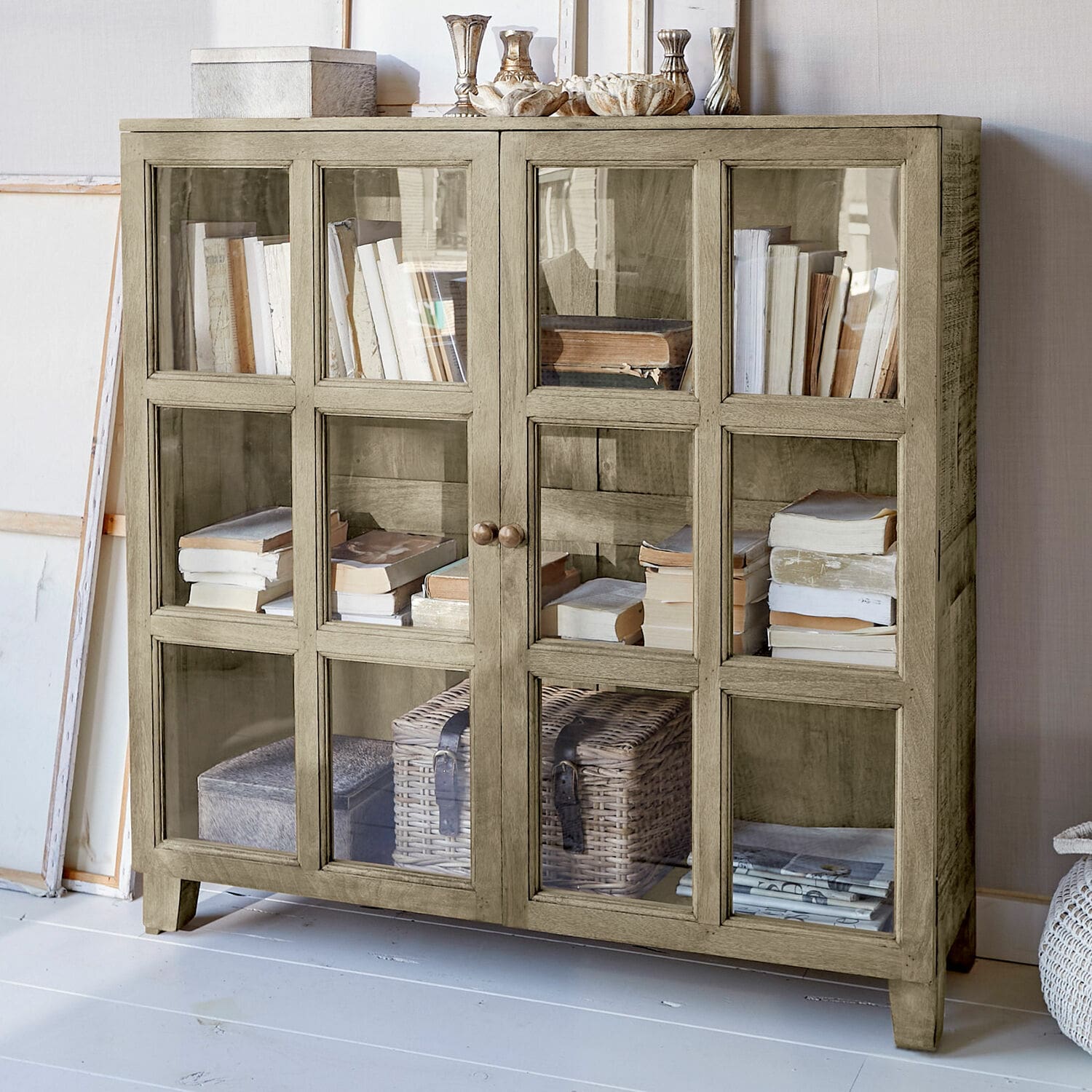 Vitrine Stoneham Buffet en bois beige avec portes vitrées, rempli de livres et décorations, meuble de salon élégant
