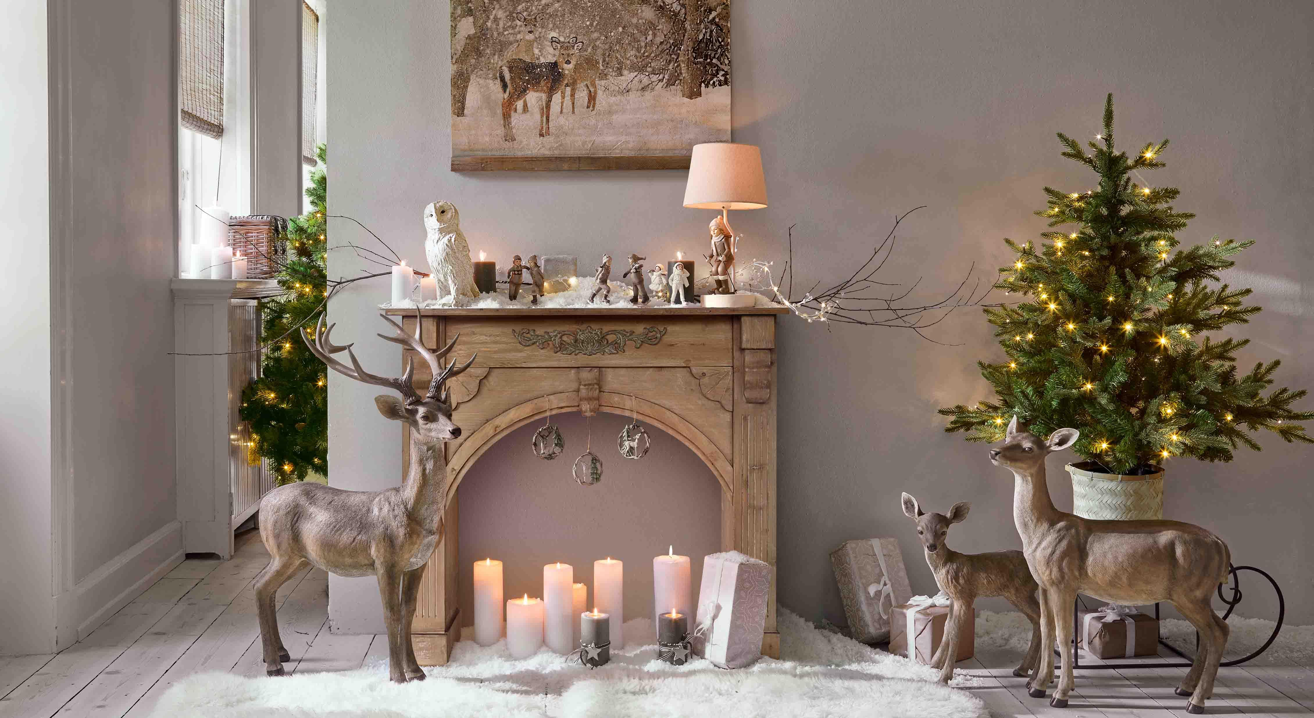 Décoration de Noël avec figurines de cerfs bruns, bougies et sapin vert illuminé par des LED