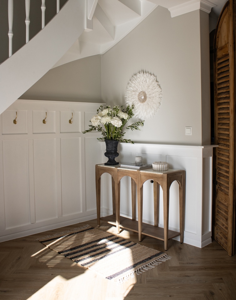 Tapis naturel beige à rayures noires avec franges sur parquet en bois clair dans un intérieur lumineux