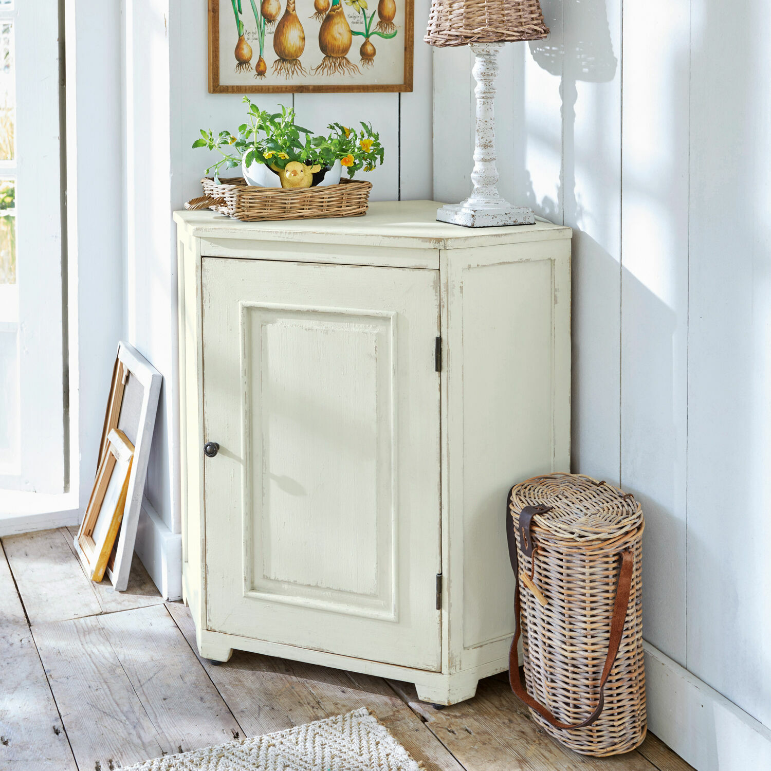 Commode d'angle Yurielka Buffet en bois crème à une porte style vintage dans une pièce lumineuse avec panier en osier