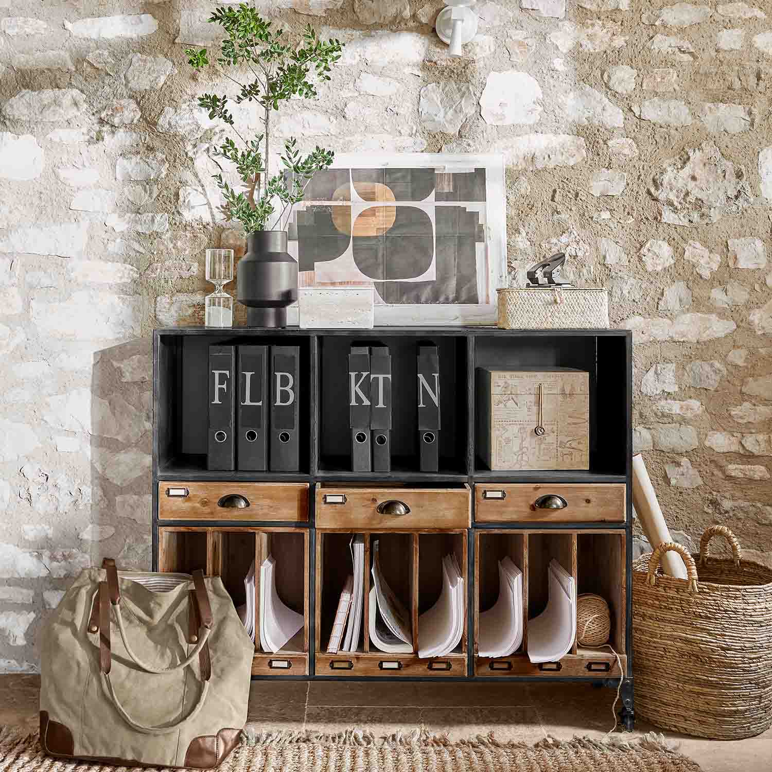 Commode noire en métal et bois avec tiroirs et classeurs devant un mur en pierre style loft