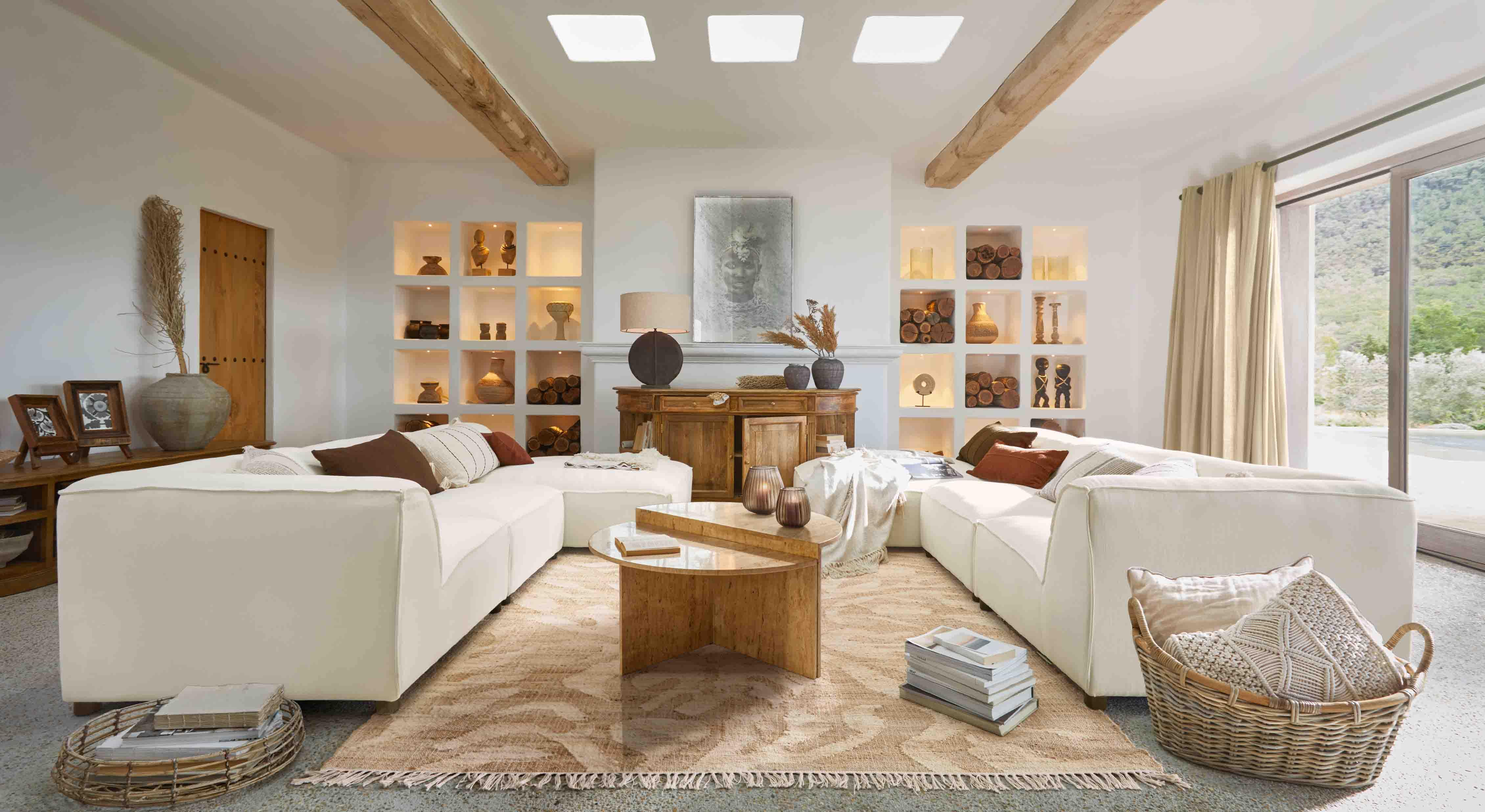 Salon spacieux avec canapé modulaire blanc, table basse en bois et décorations aux tons naturels