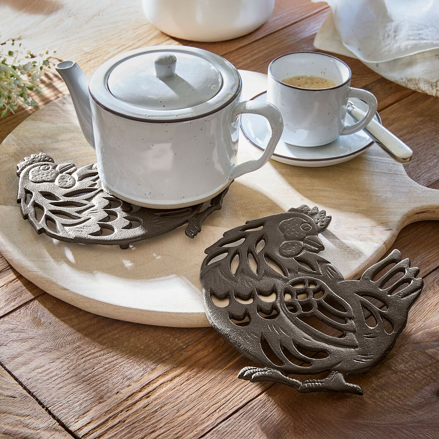 Lot de 2 dessous de plat Chavéreau Dessous de plat en fonte brun en forme de poule sur table en bois avec théière blanche et tasse