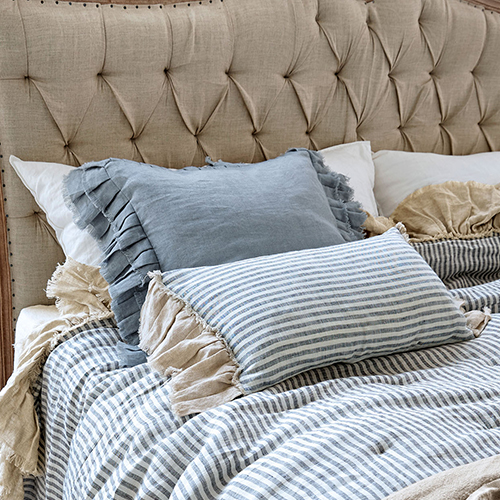 Linge de lit rayé avec coussins en lin sur une tête de lit capitonnée beige
