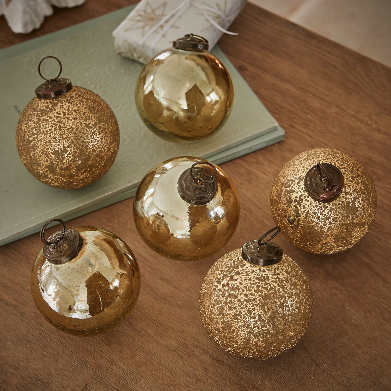 Lot de 6 boules de Noël Fioravino Ensemble de six boules de Noël en verre doré avec différentes textures posées sur une table en bois