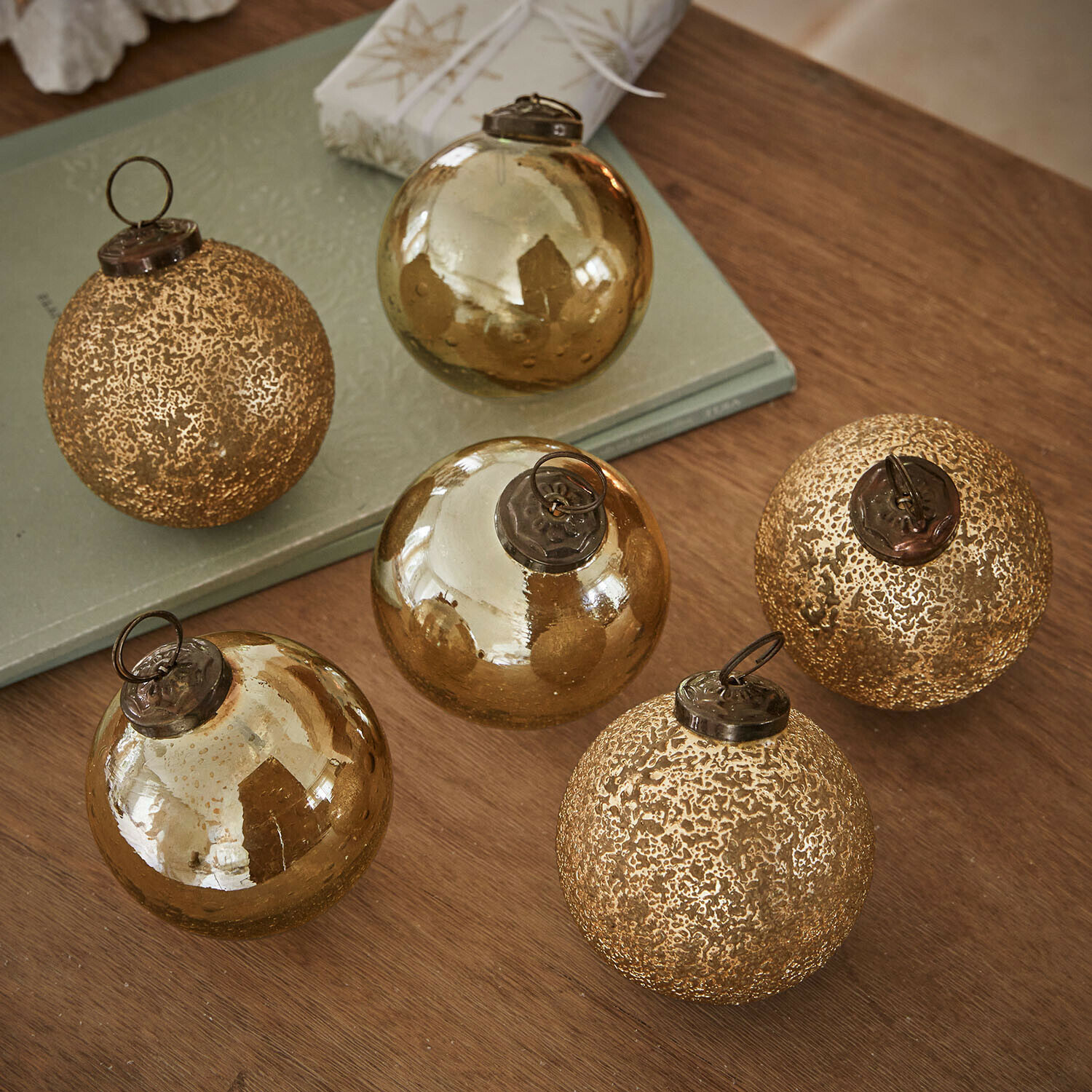 Lot de 6 boules de Noël Fioravino Ensemble de six boules de Noël en verre doré avec différentes textures posées sur une table en bois