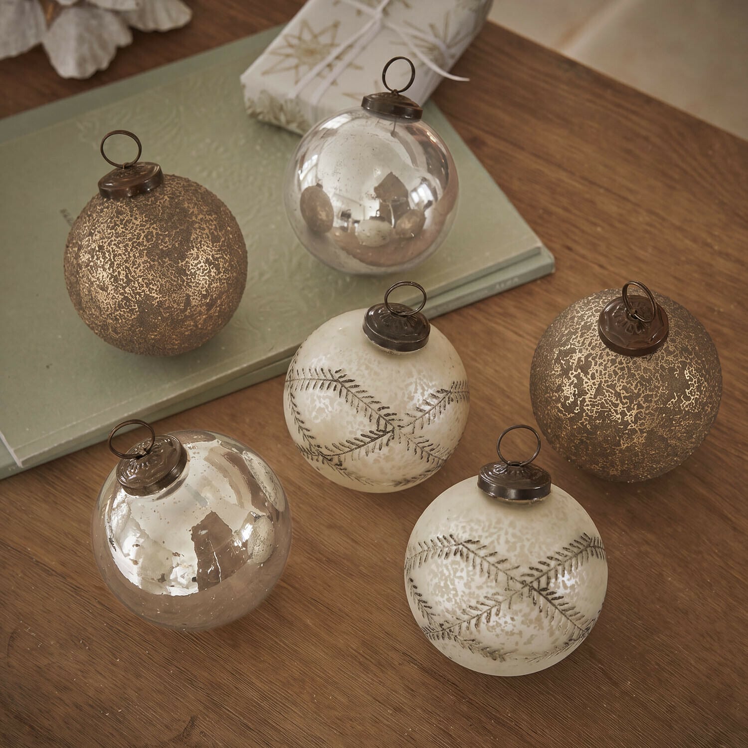 Lot de 6 boules de Noël Fioravino Ensemble de six boules de Noël en verre doré avec différentes textures posées sur une table en bois