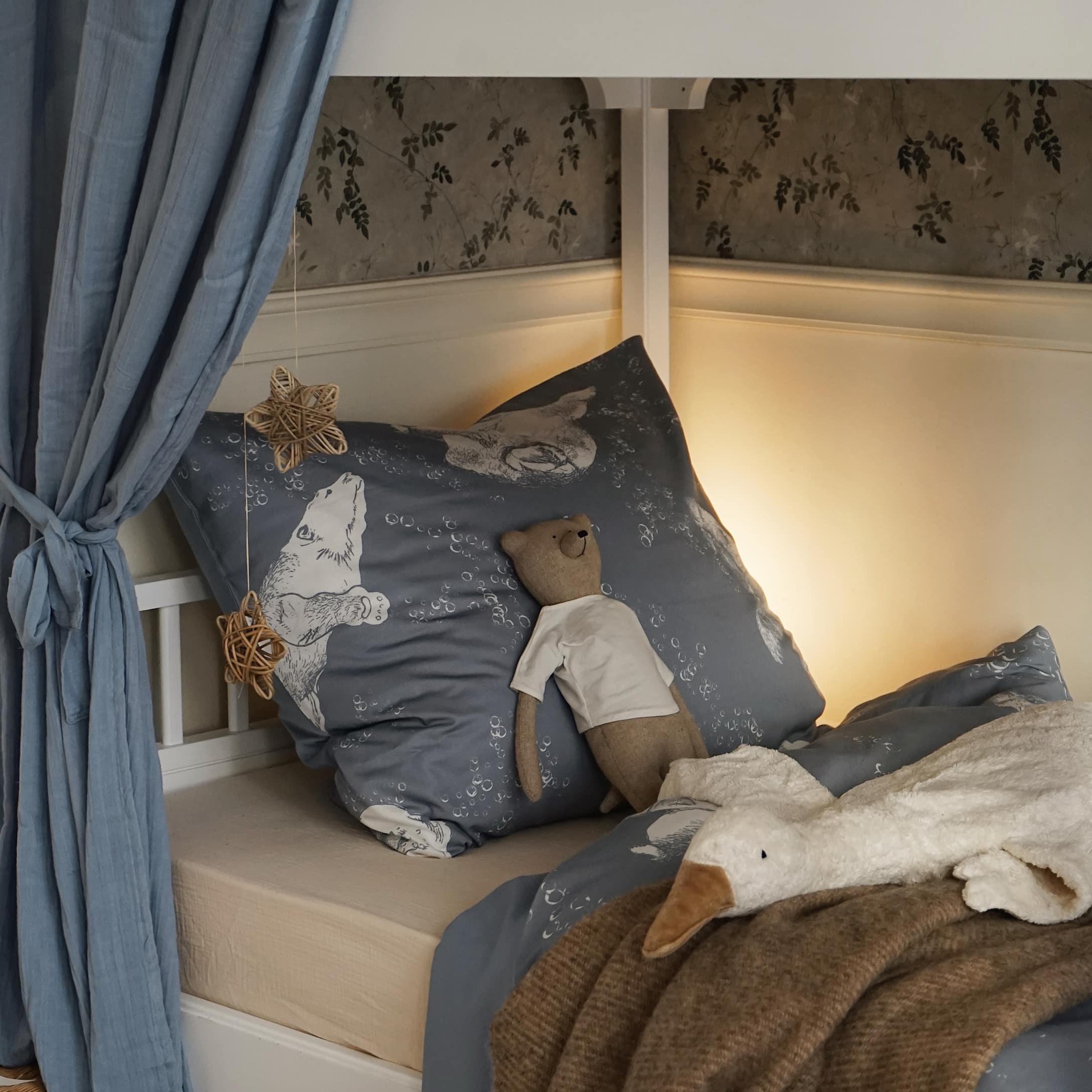 Linge de lit bleu avec motif ours et peluches sur un lit d'enfant dans une chambre chaleureuse