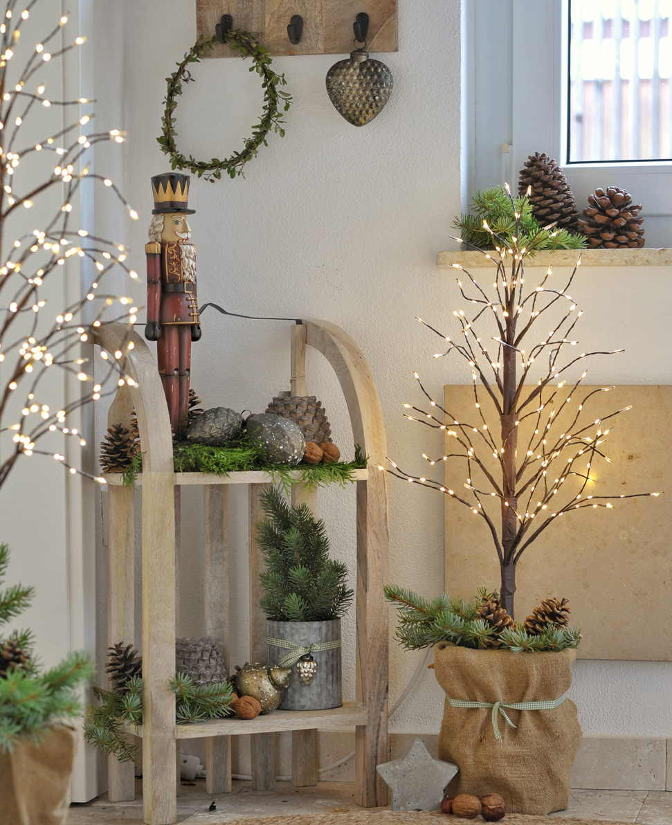 Arbre lumineux LED décoratif en sac de jute avec pommes de pin et branches vertes, décoration de Noël chaleureuse.