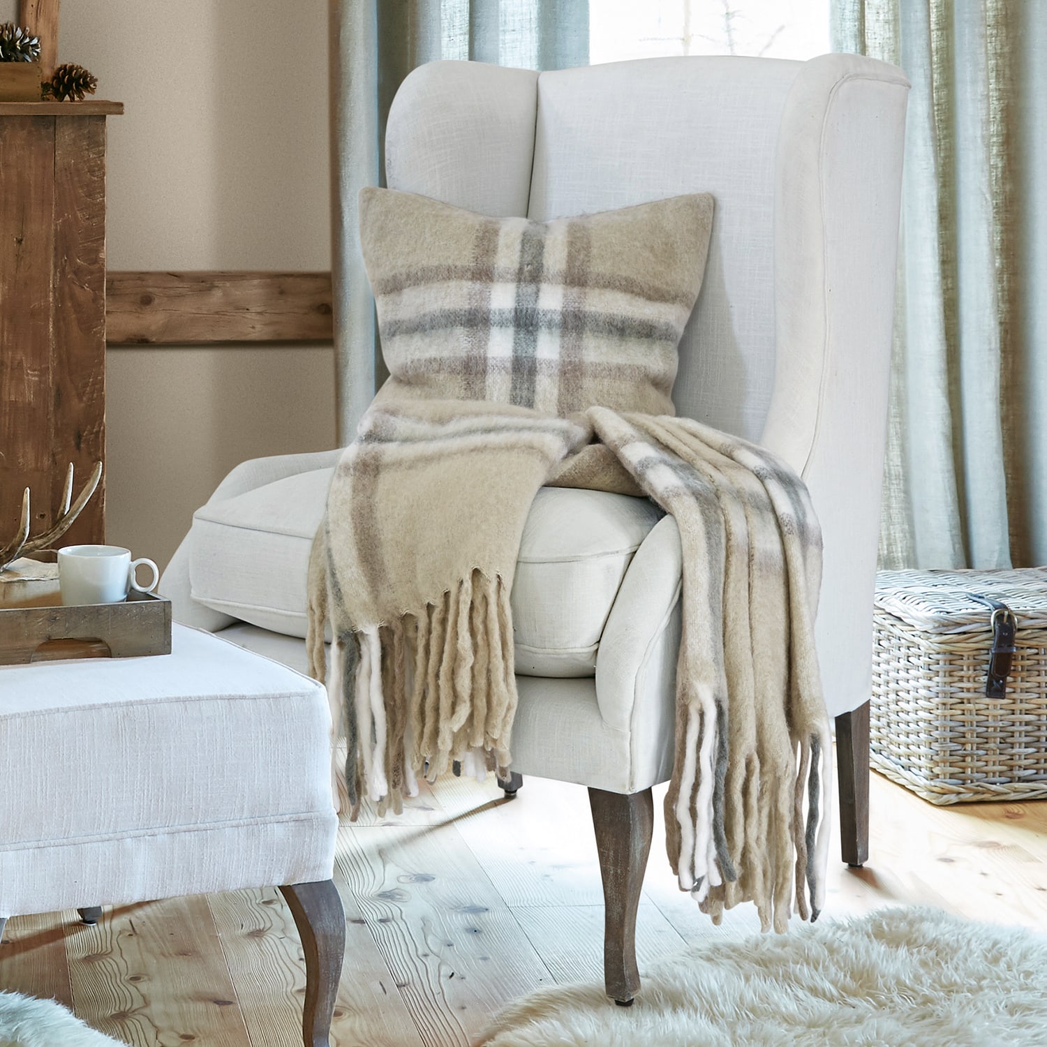Plaid et coussin en laine beige à carreaux sur un fauteuil crème dans un salon chaleureux