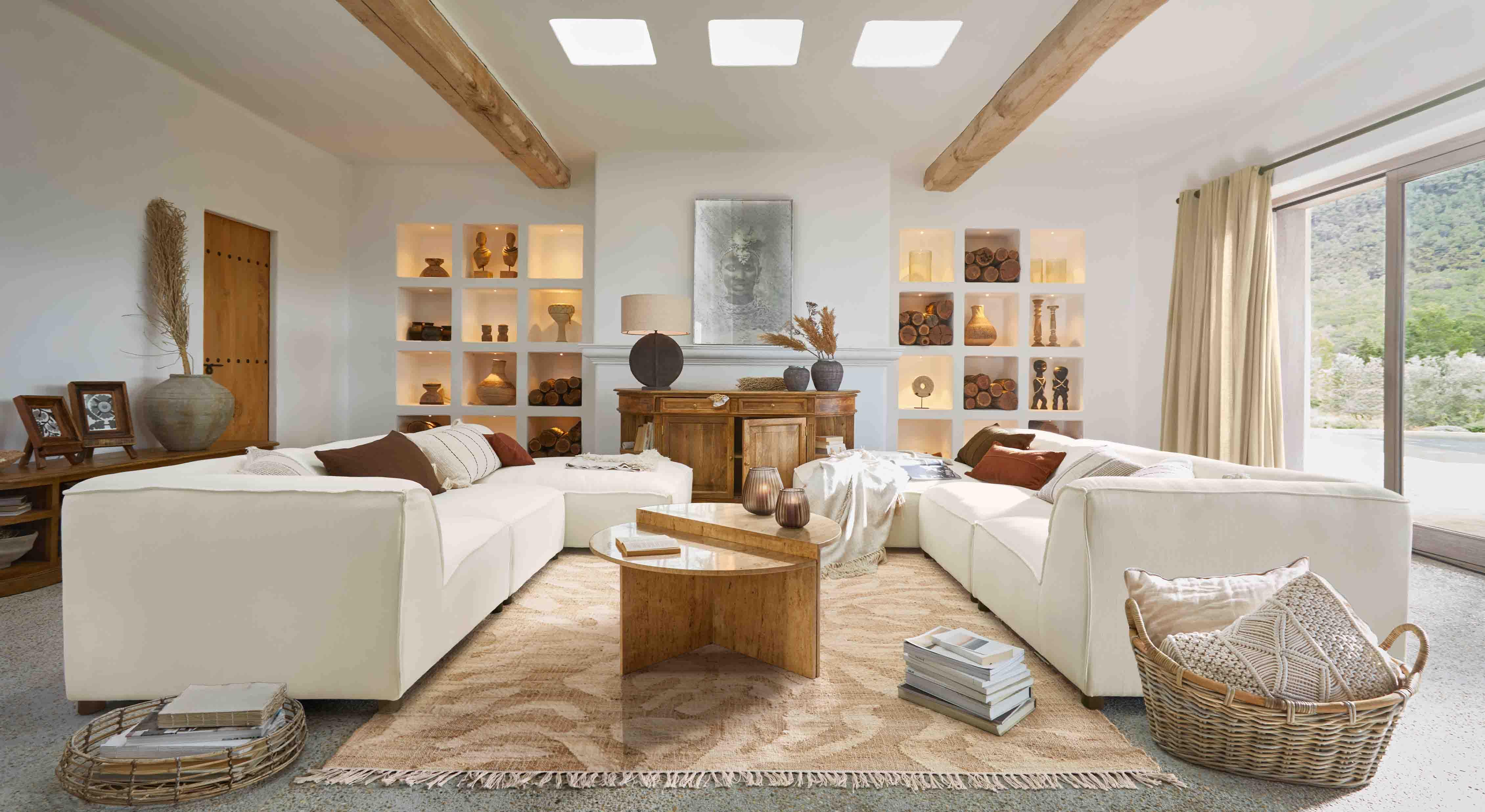 Salon spacieux avec canapé d'angle blanc, table basse en bois et décorations naturelles chaleureuses
