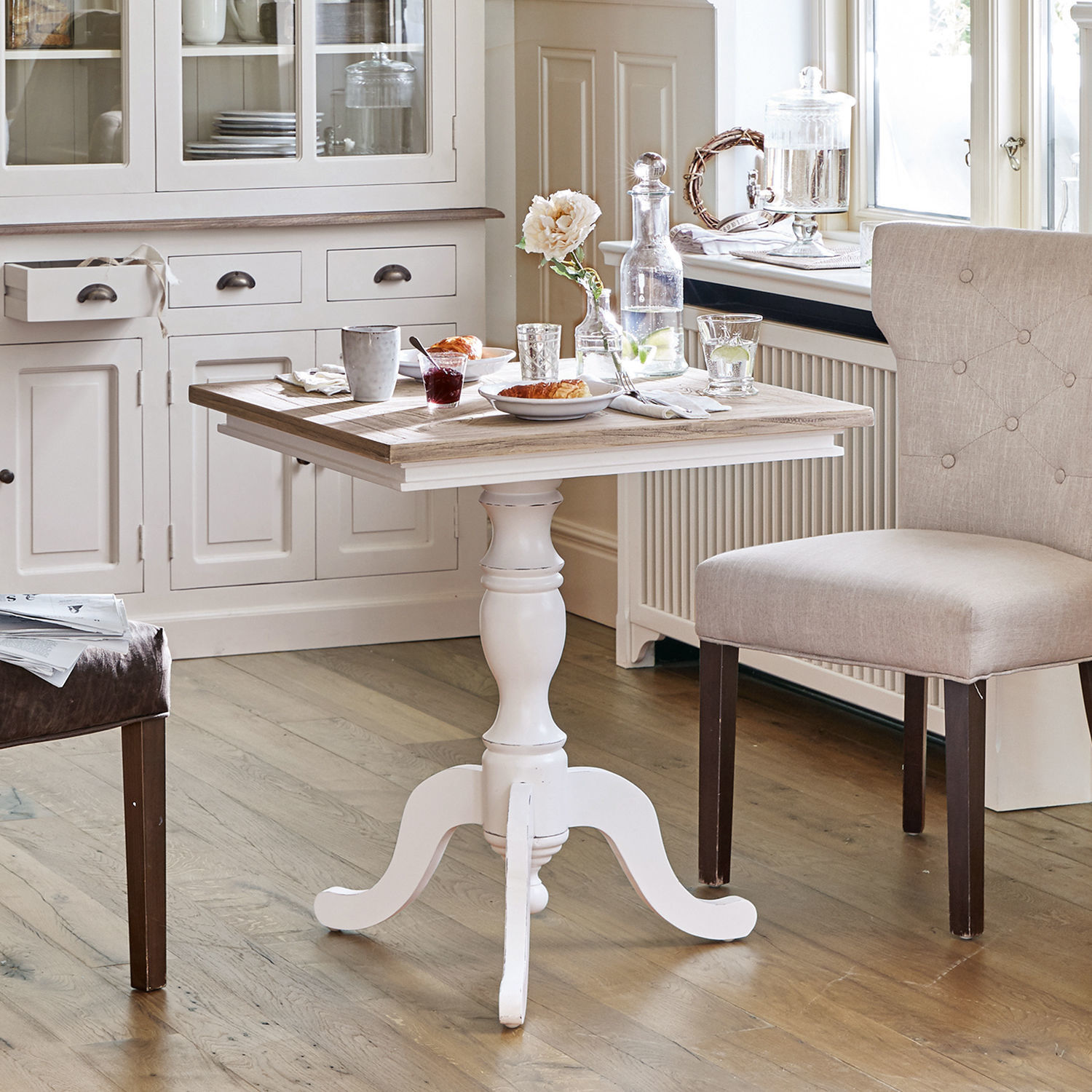 Table Kingston Table en bois blanc avec pied sculpté et plateau couleur bois naturel dans une cuisine lumineuse